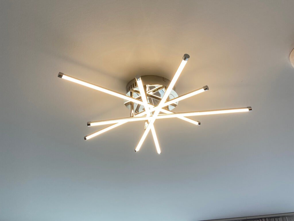 Modern starburst LED ceiling light fixture radiating bright light in a clean, contemporary room.