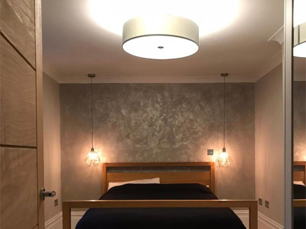 Cozy bedroom featuring bedside lights hanging from the ceiling, casting a warm, inviting glow.