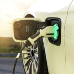 Electric vehicle plugged into a charging station, indicating a green light for charging in progress.