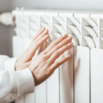 Person warming hands on an electric radiator, feeling the gentle heat on a cold day.