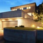 Modern home at twilight with strategic security lighting illuminating the exterior and driveway.